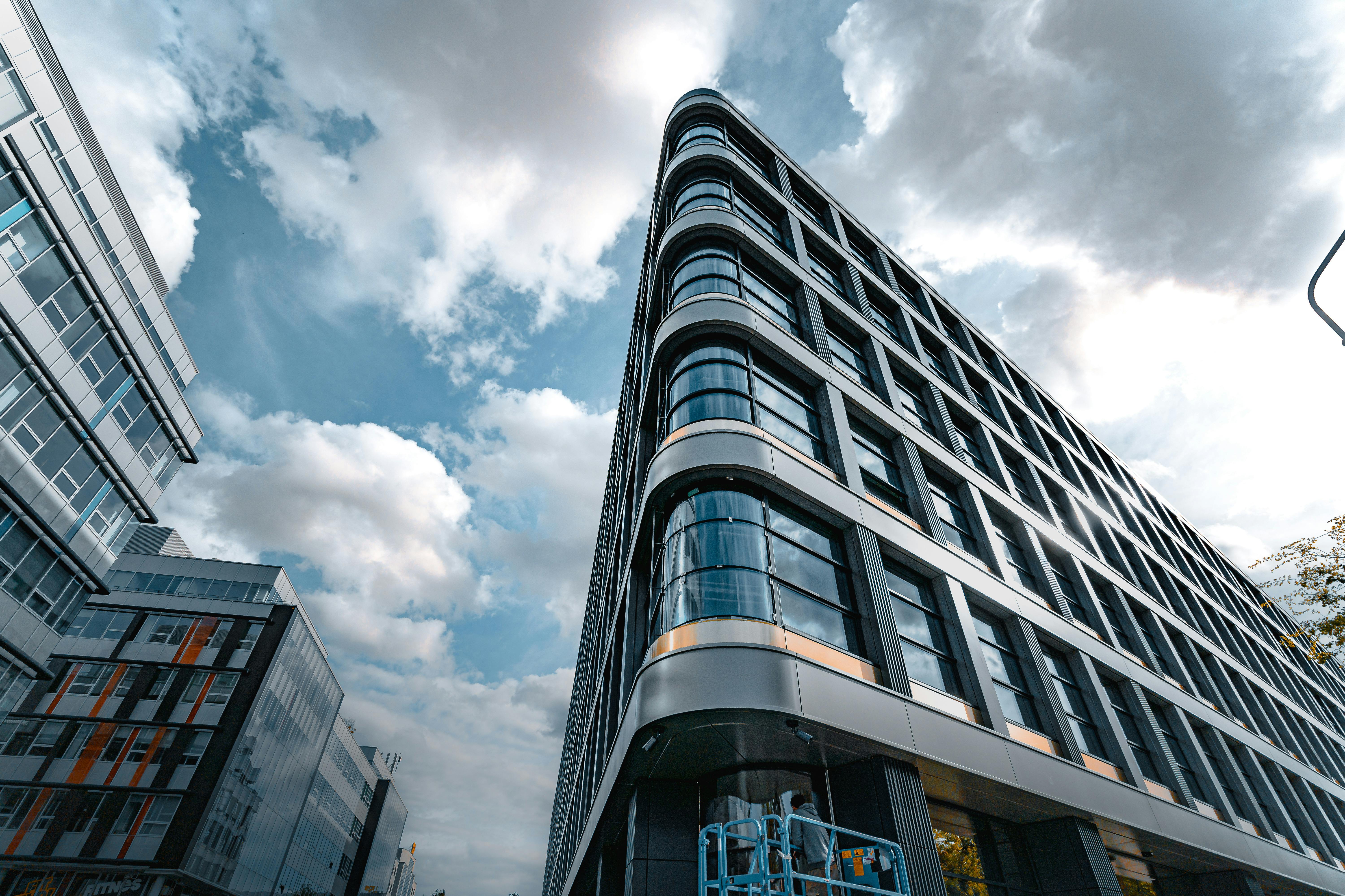 Low-angle view of a modern commercial office tower against an overcast sky.
